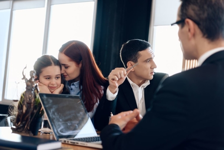 couple with child looking away from eachother in front of divorce attorney
