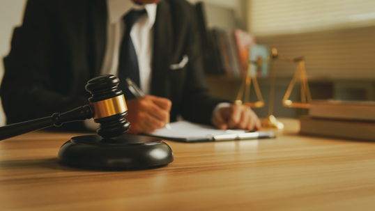 Lawyer working about law with wooden gavel on tabel in courtroom.