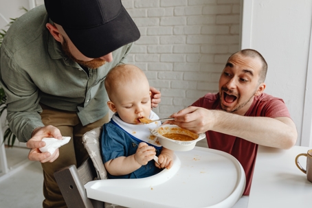gay couple feeding child together