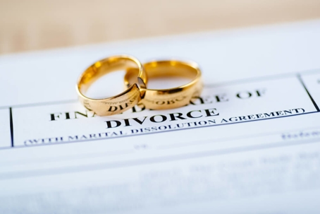 Two broken golden wedding rings divorce decree document.